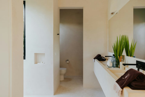 Contemporary bathroom in soft tones, featuring a wide sink and private toilet area