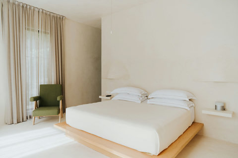 Charming bedroom bathed in natural light, featuring a plush king bed and a cozy accent chair