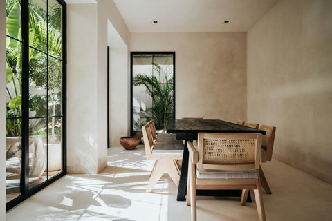 Elegant dining space with sunlight, rattan chairs, and a dark wood table