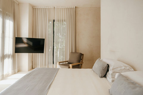 Bright bedroom with a cozy seating corner and a television,