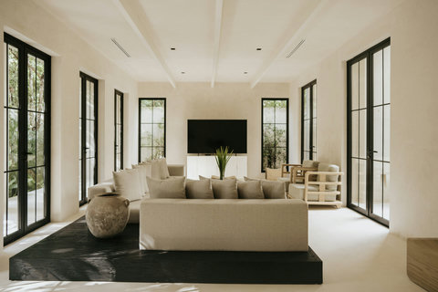 Modern living room with a minimalist palette, Smart TV, and floor-to-ceiling windows overlooking the garden