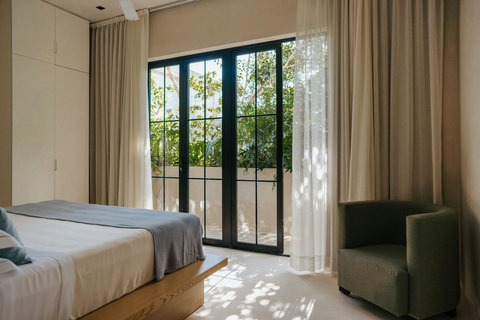 Light-filled bedroom featuring a platform king bed, accent chair and garden views