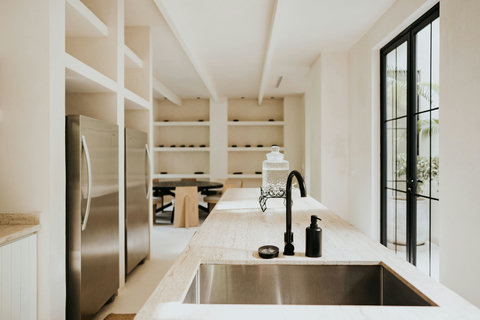 Open kitchen view with island, black faucet, and dining area framed by shelving