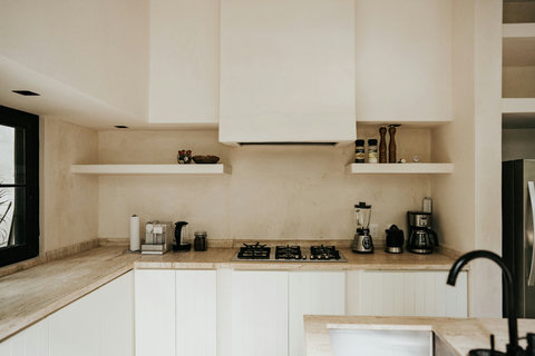 Contemporary kitchen wall with gas cooktop, stone surfaces, and coffee essentials