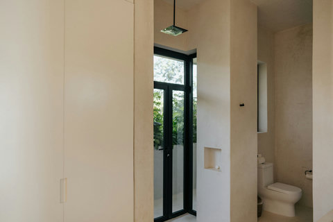 Modern bathroom with rain shower, built-in storage, and a glass door to a private outdoor view