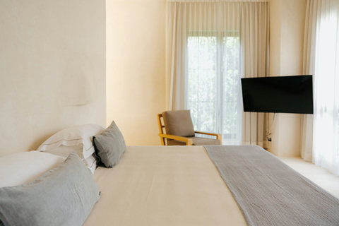 Charming bedroom bathed in natural light, featuring a plush king bed, TV and accent chair