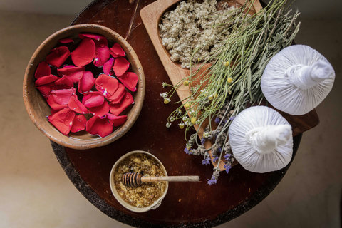 Petals, herbs, and warm oils gather softly nearby, setting a slower rhythm for the rituals that follow.