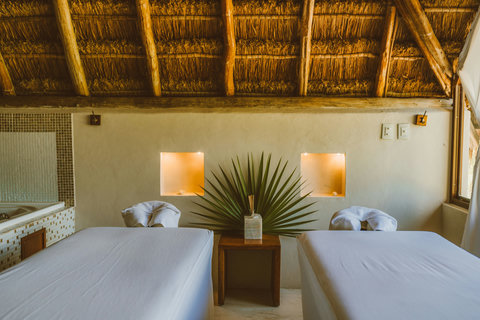 Inside, twin treatment beds wait in hush and shade, crisp linens and warm textures inviting the body to exhale.