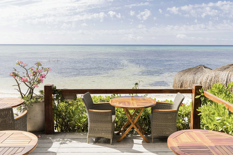 A quiet corner overlooks the calm sea, perfect for slow sips and endless views under open skies.
