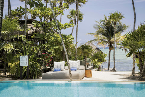 SWIMMING POOLS - Afternoon settles; striped pillows, sea breeze, and drifting conversations mingle beside crystalline water quietly licking travertine.