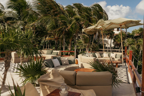 Terrace palms dance wildly, linen cushions cradle, desert-weave umbrellas shift shade as midday breeze gathers speed.