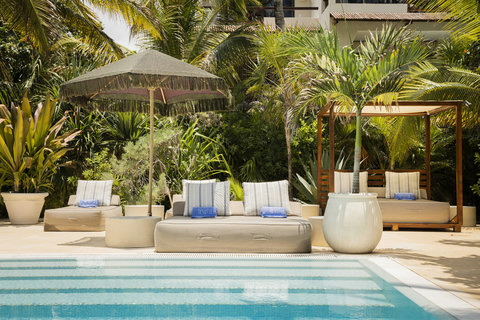 SWIMMING POOLS - Early rays scatter across fresh cushions, umbrella fringe sways, and the day resets in gentle turquoise stillness.