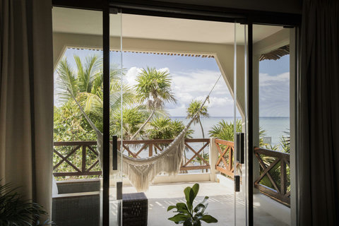 WATERFRONT SUITES - Slide doors aside, the balcony floats above jade water, macramé hammock swaying in warm midday hush.