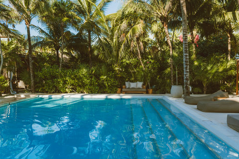 Secret bench nestled in greenery waits between afternoon laps, filtered sun flickering like liquid gold across calm blue.