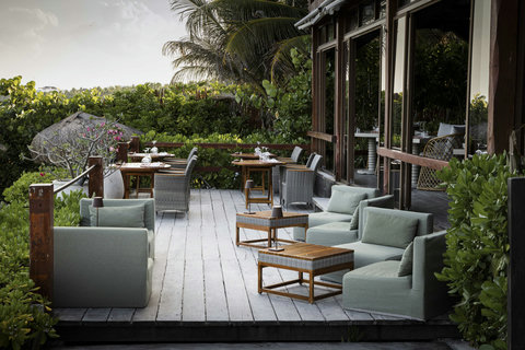 Weathered wood and soft greens create a relaxed terrace where the breeze moves freely through lush surroundings.
