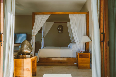 SUITE - Drift through the doorway into a bedroom wrapped in soft light, where crisp linens and warm wood invite you to pause and let the stillness settle in.