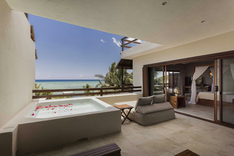 Step barefoot from bed to terrace where glass walls dissolve boundaries, letting ocean air mingle with linen sheets and the tub’s floral scent linger in the golden afternoon hush.