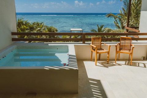 Let sunlight trace patterns on stone as you settle into teak chairs beside turquoise steps, watching waves roll in slow rhythm beyond palm fronds that sway like quiet sentinels.