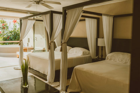 Let ceiling fans stir warm air as daylight spills from terrace to bed, each canopy tied back like an invitation — to linger, to breathe, to let the jungle’s glow settle into your bones.