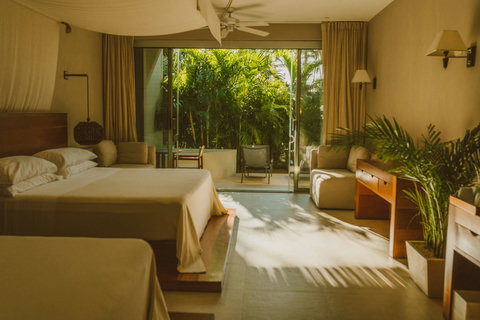 SUPERIOR DOUBLE DELUXE SUITES - Drift between beds draped in flowing veils as golden hour spills through glass doors, blurring inside and out until the room feels like an extension of the jungle’s gentle hush.