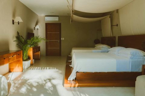SUPERIOR DOUBLE DELUXE SUITES - Rest beneath suspended fabric that catches the afternoon glow, while palm shadows dance on tile floors and wooden dressers hold space for slow rituals and unhurried breaths.