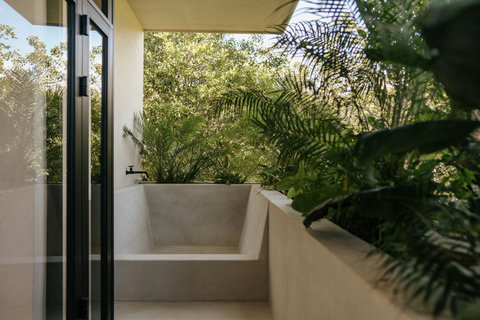 Relaxing outdoor tub on a balcony amid tropical plants and glass accents