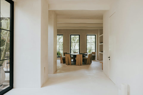 Round dining table set with sculptural wood chairs and outdoor views