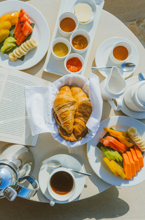 PANDANO RESTURENT - Breakfast unfolds in sunlight: flaky croissants nestled in linen, vibrant fruit sliced beside steaming coffee, all laid out like an invitation to linger, read, and savor the morning hush.