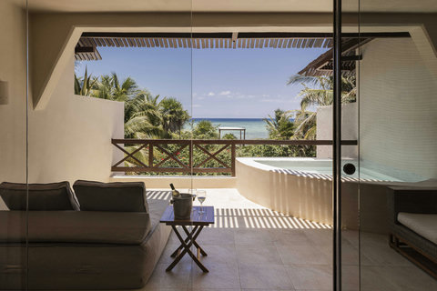Sip chilled wine on a shaded terrace where glass walls frame ocean views, letting slatted light stripe the stone as you sink into linen loungers beside a private plunge pool.