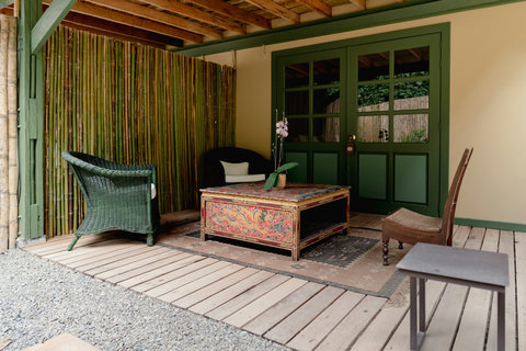 Living Room - Escape to a tranquil oasis where rustic charm meets modern comfort. Bask in the warm glow of ambient lighting as you unwind in this cozy patio, surrounded by natural bamboo accents. Perfect for sipping your morning coffee or enjoying a peace