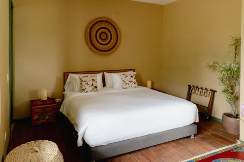 Bedroom - Unwind in a cozy oasis where natural light meets rustic charm. This inviting bedroom offers a plush king-sized bed adorned with soft linens and floral accents, perfect for restful nights. The serene ambiance, complete with earthy tones and a t