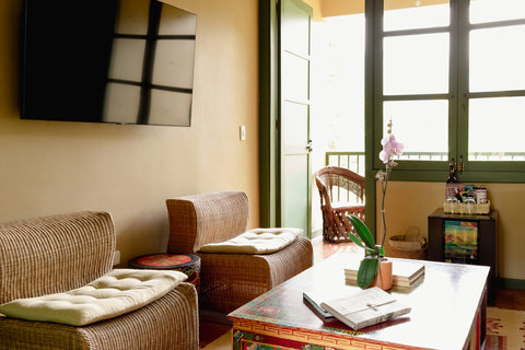 Living room - Immerse yourself in a serene retreat, where natural light dances across cozy wicker seating, and an intimate balcony invites you to unwind. Enjoy modern comforts with a touch of elegance, perfect for a relaxing getaway.