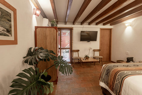 Bedroom 1 - Discover serenity and style in this cozy retreat, where warm lighting and rustic beams create an inviting embrace. Unwind in your private nook with a hammock waiting for you just outside the door, offering the perfect spot to relax under the o