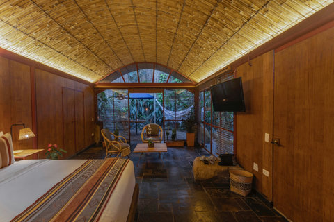 Bedroom 2 - 🌿✨ Immerse yourself in this tropical oasis, bathed in warm ambient lighting. Unwind in style with a luxurious bamboo ceiling, cozy seating area, and a stunning garden view right from your bed. Perfect for a restful retreat with all the modern