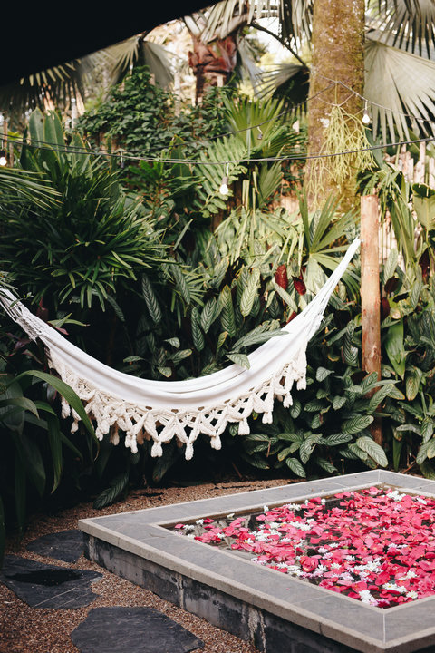 Hammock patio area - Escape to your own tropical paradise where the gentle sway of the hammock and the soft glow of string lights create the perfect oasis. Surrounded by lush greenery and a sparkling flower-adorned spa, this serene retreat promises relaxa