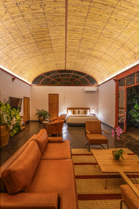 bedroom 1 - Step into serenity with this spacious retreat, featuring warm, ambient lighting and elegant design. Relax in style with plush seating, a king-size bed, and lush greenery just outside your door. Your perfect getaway awaits.