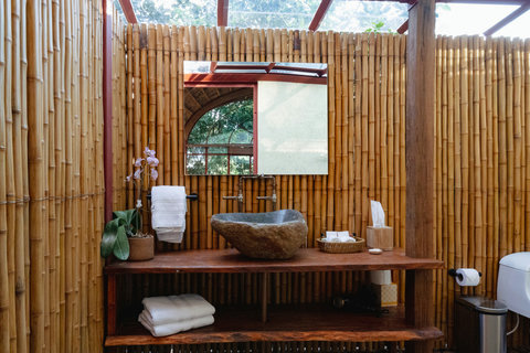 Bathroom sink - Experience tranquility in this serene bamboo oasis, featuring a luxurious stone basin and dappled sunlight filtering through the canopy above. A perfect blend of natural elegance and modern comfort awaits you.
