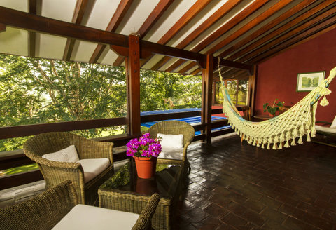 Living Room - 🌿 Relax in nature's embrace as you unwind in this cozy, sun-drenched veranda. With its inviting wicker seating and charming hammock, it's the perfect spot to sip your morning coffee or enjoy tranquil sunset views. Escape to your own private