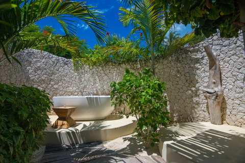 Tucked behind coral stone and palms, this open-air bath feels private, warm, and made for lingering a little longer.