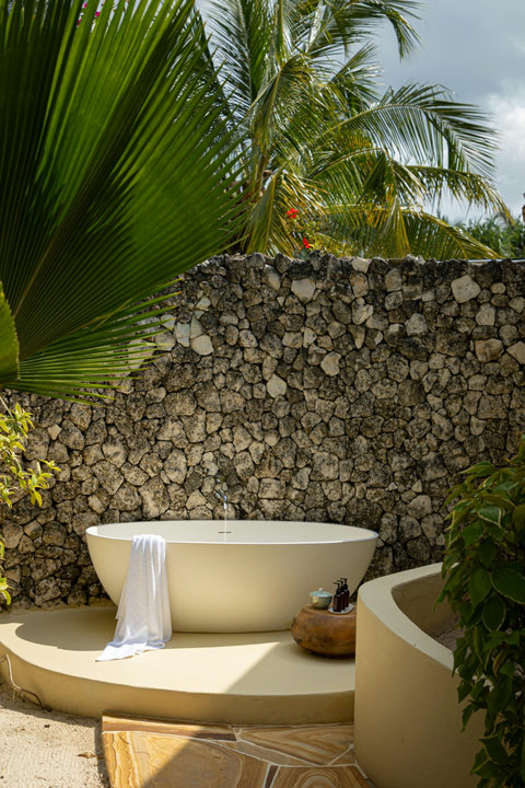 Soak outdoors beneath swaying palms, where sun-warmed stone and garden stillness turn the moment into pure escape.