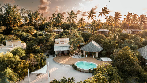 At sunset, the villa glows through the palms, private, grounded, and wrapped in that end-of-day softness.
