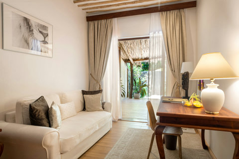 Sheer curtains lift with the breeze, and the light turns honeyed, drawing the indoors softly back toward the garden.