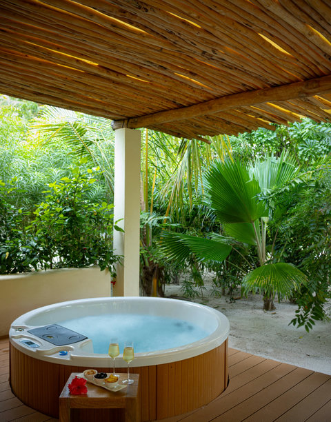 Outside, the hot tub hums gently beneath the timber roof, wrapped in green shade and an easy afternoon hush.