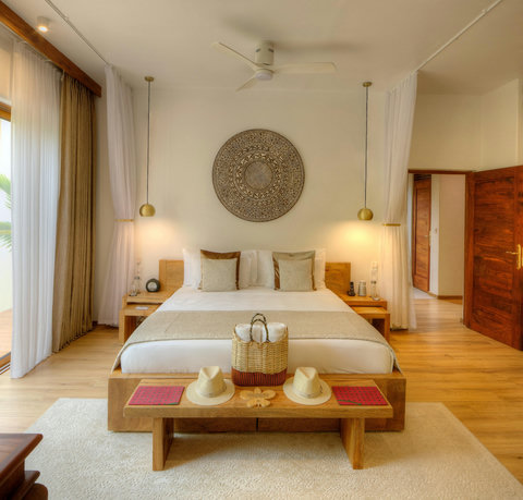 A centered bed, soft pendants, and sun hats waiting at the bench, the day unfolding quietly.