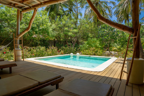Just beyond the doors, the pool waits under dappled shade, inviting a slow dip and a long exhale.