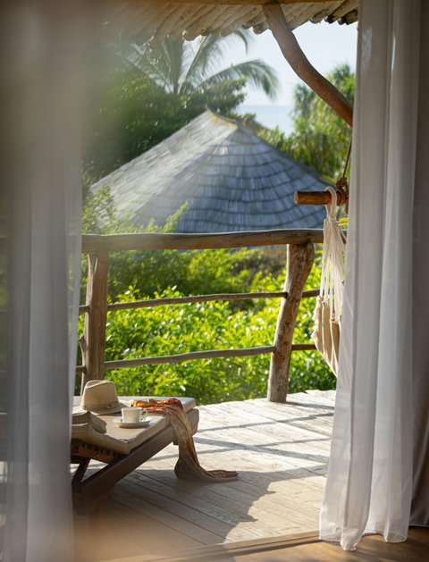 Through the curtains, coffee and sea air wait on the terrace, easing the morning into something softer.