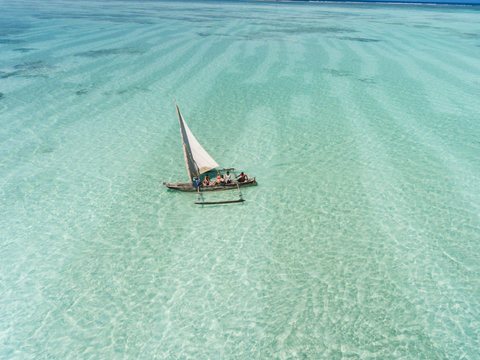 Out on clear water, the sail leans into the breeze, and the horizon keeps widening.