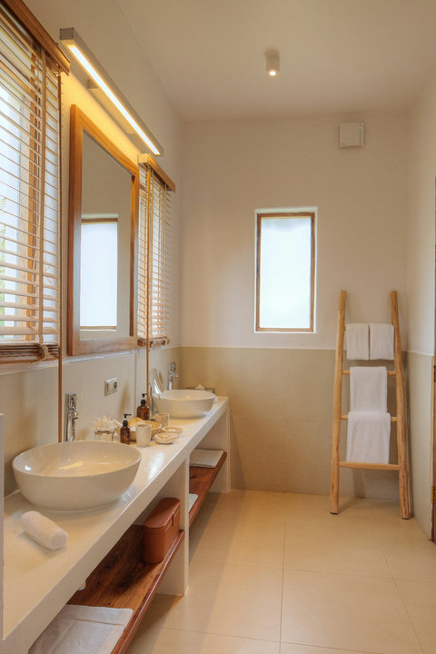 An open-air rinse, clean stone underfoot, and mirrors catching morning light with quiet clarity.