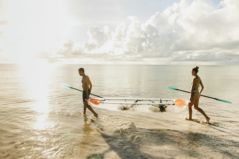 Golden hour pulls you toward the shoreline, carrying the kayak together, feet in water, minds unbusy.