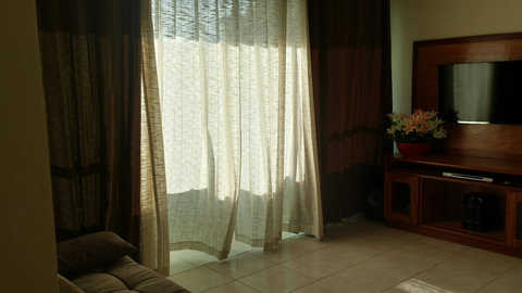 Sala de estar com: smart tv 50", aparelho de som 3 e m 1, sofá e cortinas.